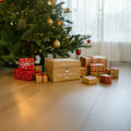 A photo of the Santa Surprise gift box by Nuby laid under a Christmas tree. This is surrounded by a range of Christmas gifts that have been neatly wrapped.