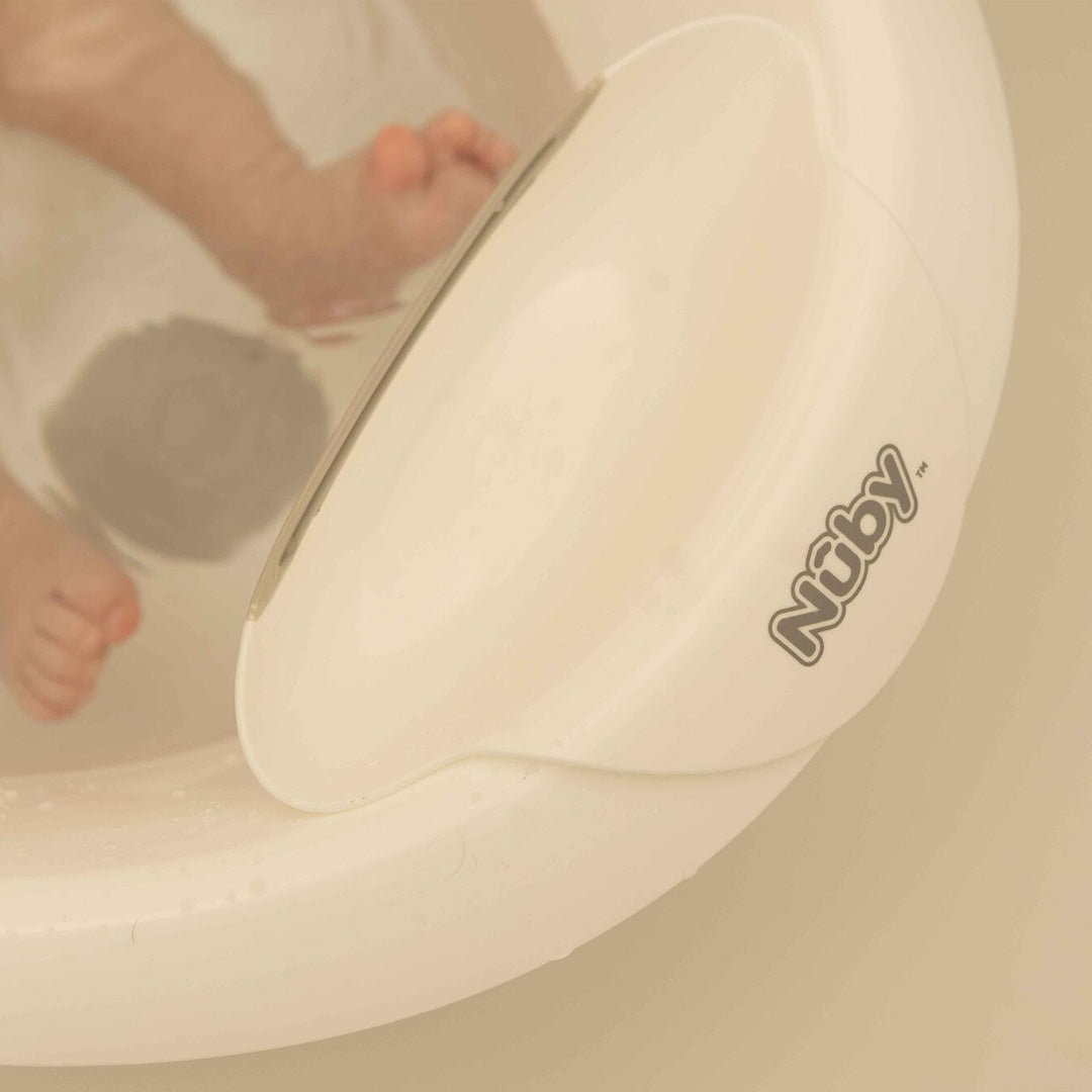 A close up of the sit up bath by Nuby with a baby's feet inside the bath.