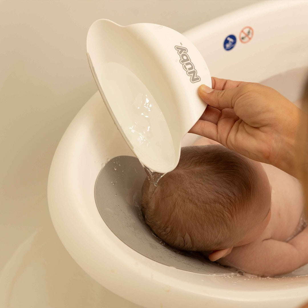 Water being poured on a baby's head in the sit up bath created by Nuby.
