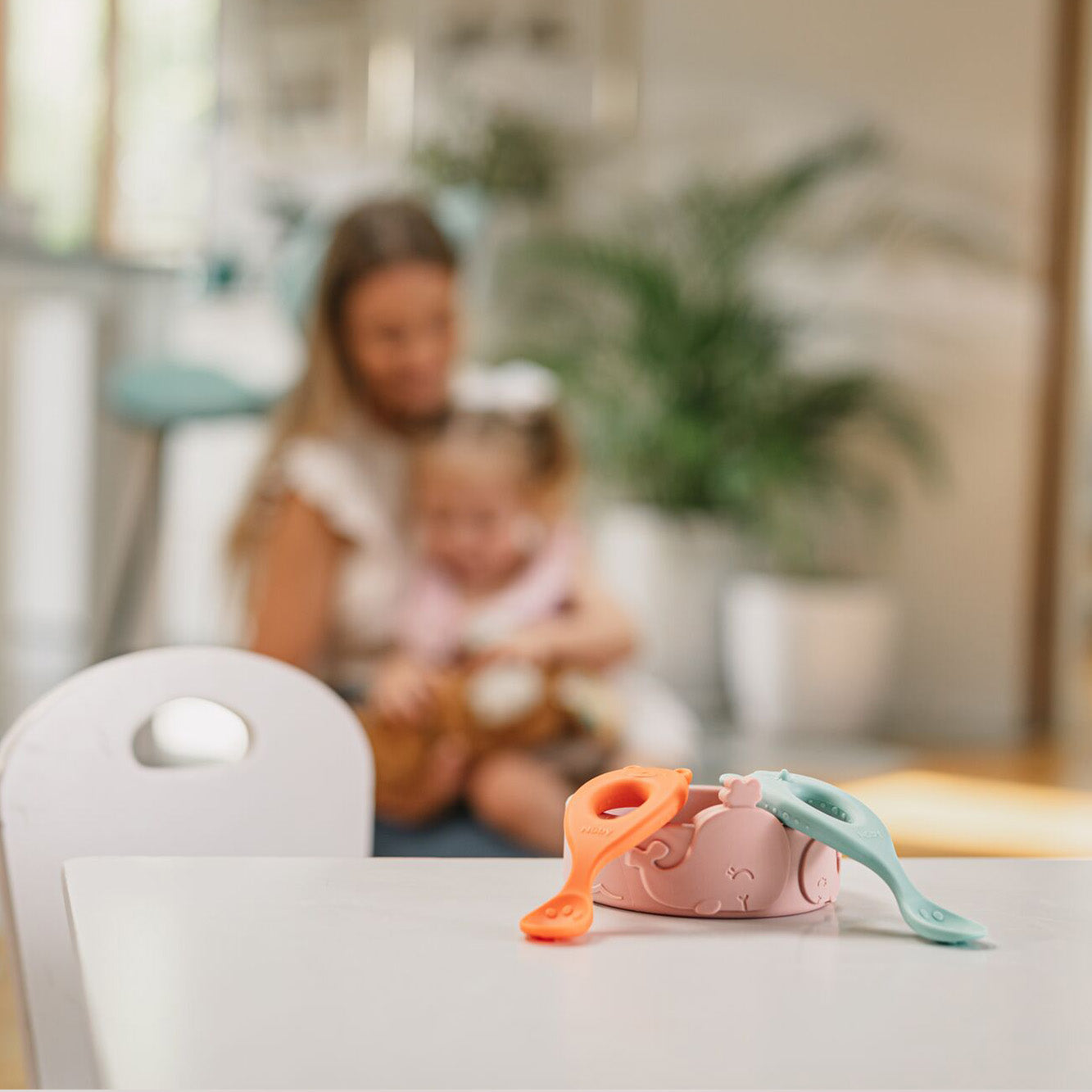 The easy grip spoons by Nuby sat on a table top as part of a young child having a meal by using them.