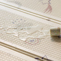 A small spill of clear liquid and a white cup with colorful sprinkles rest on the Nuby Foldable Play Mat, Stars—a soft mat with a textured surface featuring subtle star and line patterns.