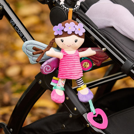 The Things with Wings Hattie Pram Toy is a colorful plush fairy doll with wings, a flower headband, and teething rings that hangs from a stroller handle. Perfect pram and teething toy for little ones on the go.