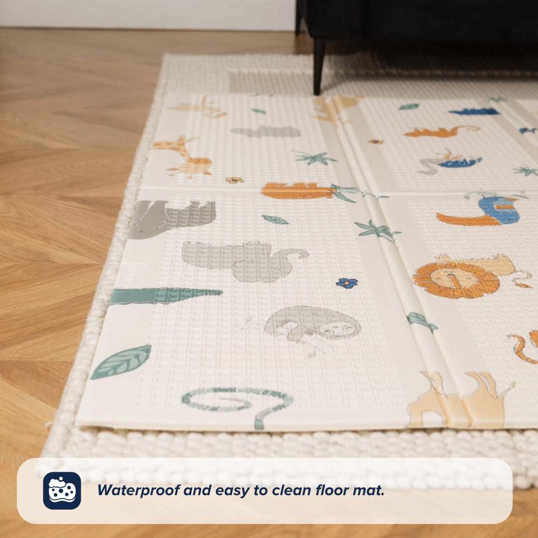 The Nuby UK Animal Adventures Floor Play Gym Set, featuring animal illustrations, is shown on a textured rug over a wooden floor. Text below reads: Waterproof and easy to clean floor mat.