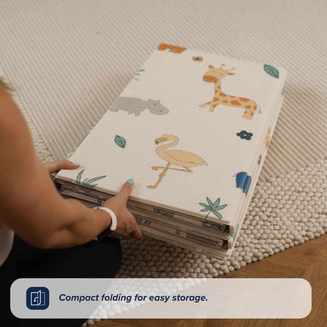 A person folds the Nuby UK Animal Adventures Floor Play Gym Set with giraffe, hippo, and flamingo designs on a beige carpet. Text overlay: Compact folding for easy storage.