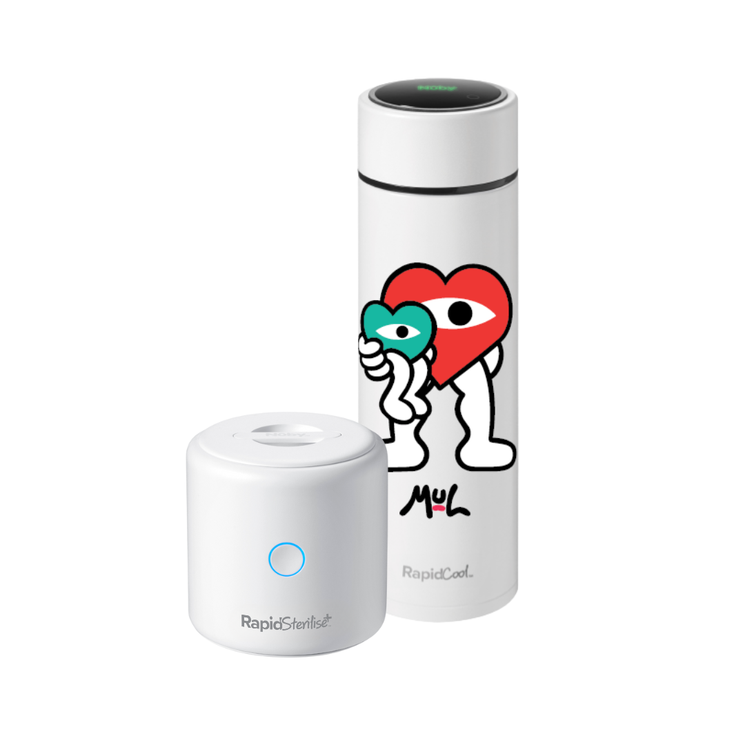A white cylindrical bottle with a colorful cartoon heart and signature stands next to the Nuby UK Cool and Sterilise, a small round white device labeled Rapid Sterilizer.