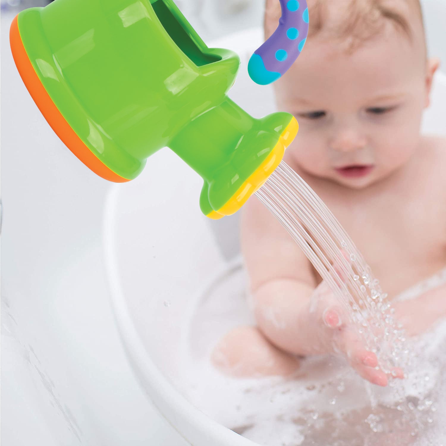 A baby playing in the bath with the water coming out of their Nuby watering can.