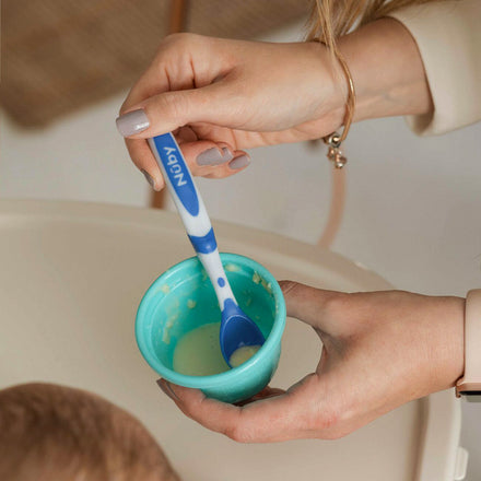A woman's hand holding the blue Weaning Spoon by Nuby.