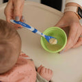 A woman holding the blue Weaning Spoon by Nuby to get food from out of a container.