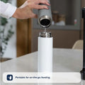 A hand pours water from a gray Nuby RapidCool™ Baby Bottle Maker into a white bottle on a countertop. Caption reads, Portable for on-the-go feeding—perfect for travel with the RapidCool™ Twin Pack.