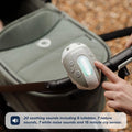 A hand presses a button on a Nuby UK sound machine, the Jitterbug Pram Rocker, attached to a stroller handlebar. Text overlay highlights 20 soothing sounds and a 15-minute cry sensor—perfect for any pram or pushchair.