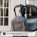 The Nuby UK Pram and Pushchair Accessories Bundle includes a grey backpack clipped to a pram handle, plus hanging plush toys. Caption: Easy to attach to most prams.