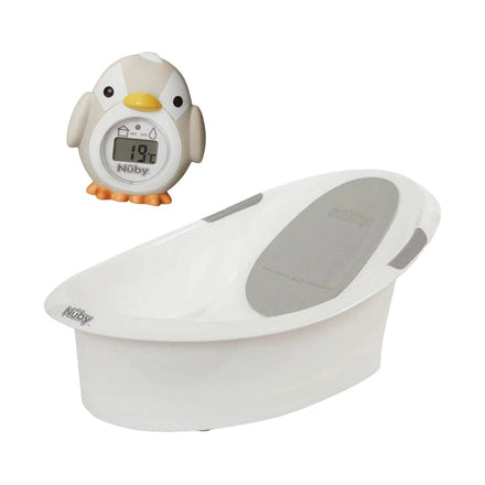 The Nuby UK Newborn Bath & Thermometer Bundle features a white baby bathtub with gray pads and a round penguin-shaped bath thermometer showing 19°C—ideal for a safe and comfy newborn bath time.