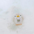 The Nuby UK Newborn Bath Support & Thermometer, shaped like a duck, displays 37.7°C while floating in soapy bubbles next to a cushioned baby bath.