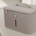 A light gray, rectangular Nuby 3 Minute UV Baby Steriliser case with a top handle, dual zipper pulls, and a small circular NOLUV logo on the front is placed on a smooth, light-colored surface.